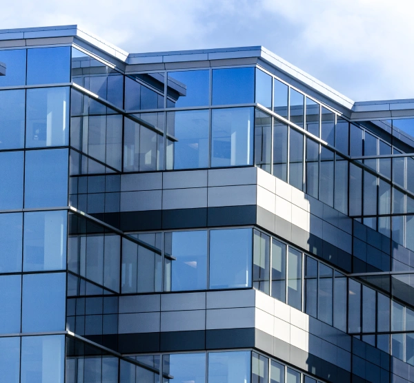 Exterior view of a modern commercial office building with blue glass windows and grey cladding panels