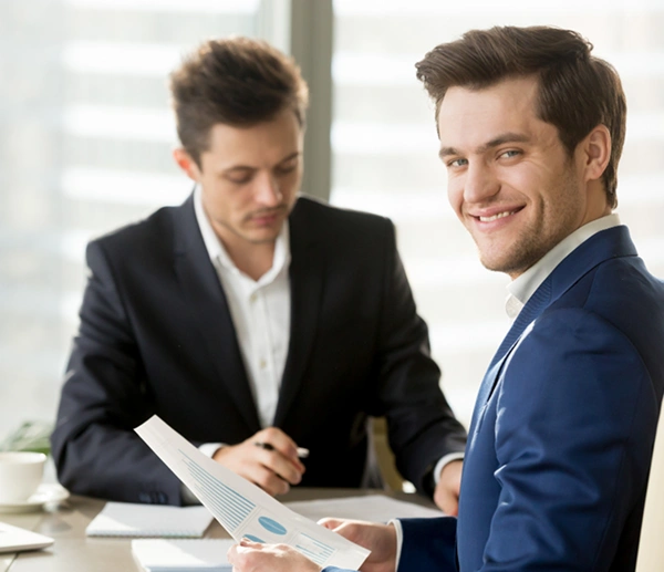 Oracle RMS website section for home business key professions showing a businessman in a blue suit smiling at the camera during a consultation meeting next to an industry list.