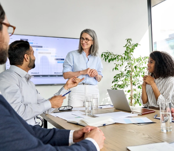 Oracle RMS website section for professional services key professions showing a team of corporate advisors collaborating around a wooden conference table next to an industry list.