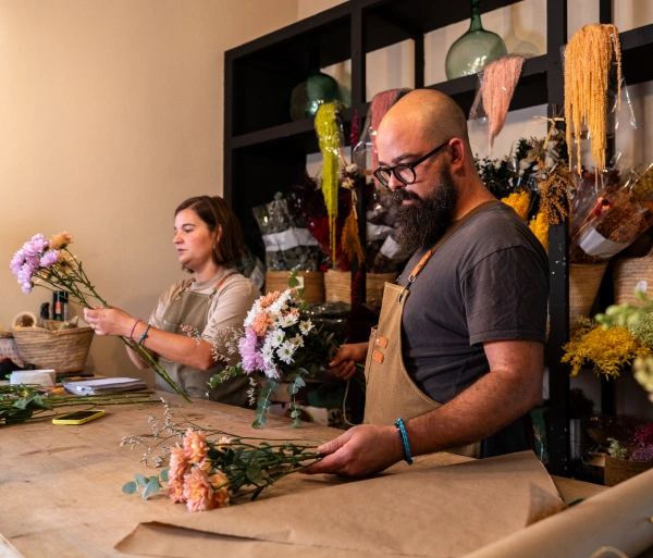 Oracle RMS website section for small business key professions featuring a male and female florist arranging bouquets in a flower shop next to a professional list.